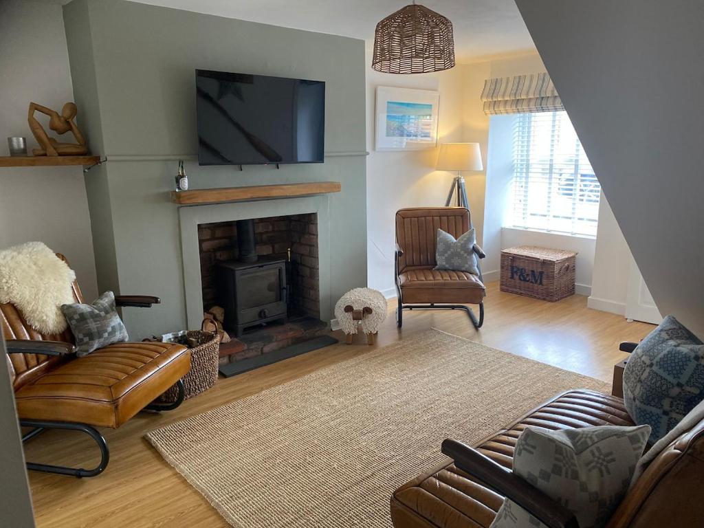 ein Wohnzimmer mit einem Kamin und einem Flachbild-TV in der Unterkunft Charming, stylish cottage, parking , large private Garden, well located for island highlights in Gaerwen