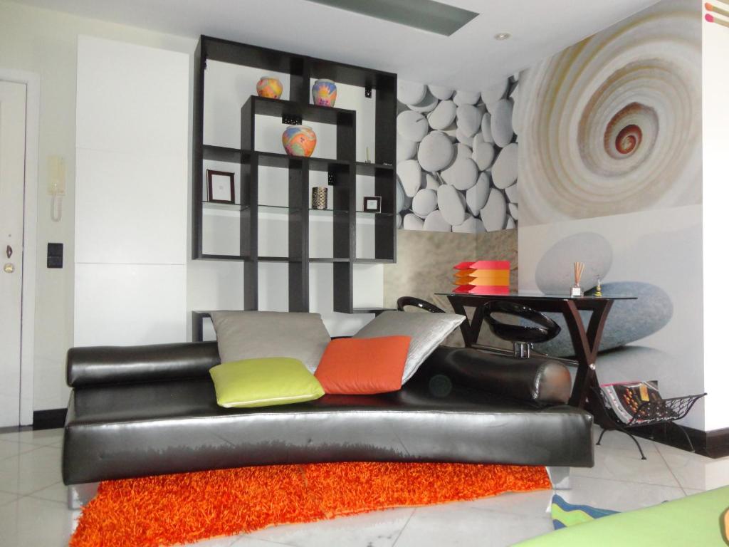 a living room with a black leather couch with colorful pillows at Apartamento Raio de Sol in Caniço