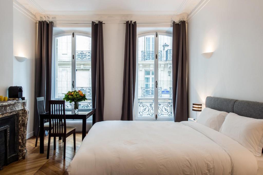 a bedroom with a bed and a desk and windows at Paris Square in Paris