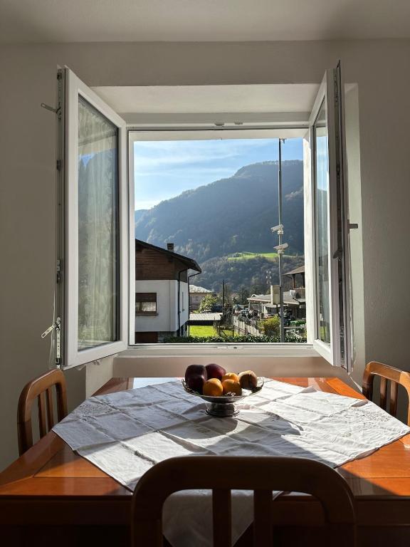 a table with a bowl of fruit and a large window at Casa Verde Valsassina 2 in Primaluna