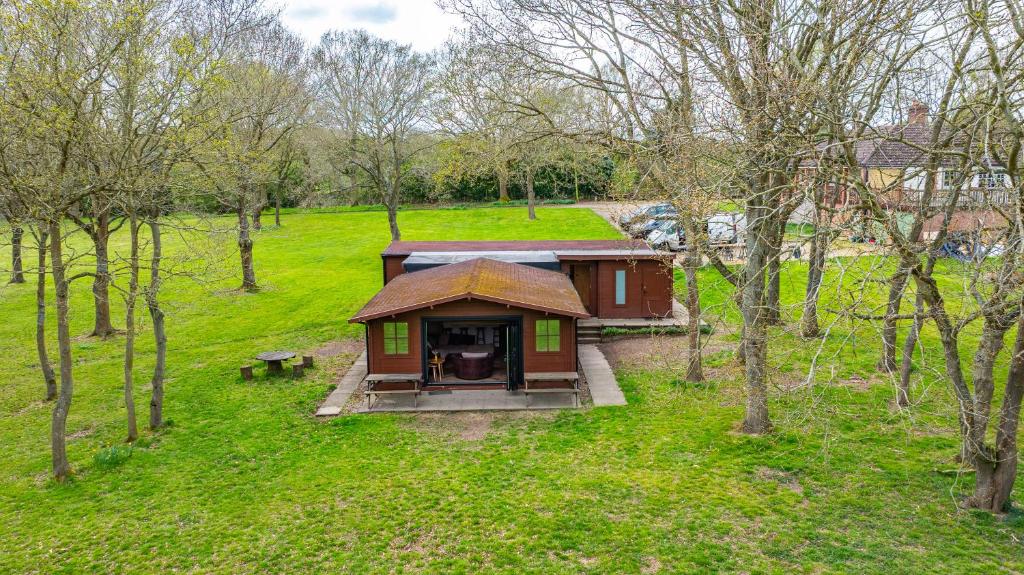 a small cabin in the middle of a field with trees at Countryside Cabin on 5 Acres Countryside with Outdoor Firepit, Cinema and converted Stables in Sible Hedingham