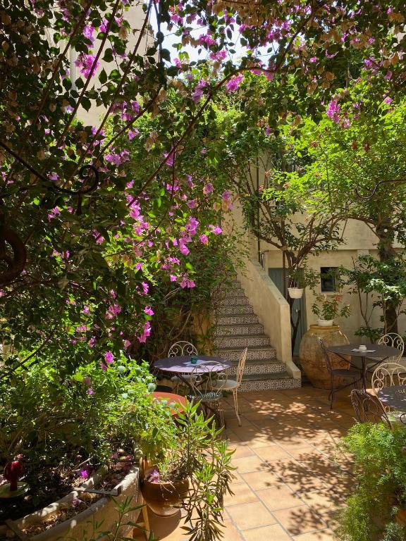 - une terrasse avec une table, des chaises et des fleurs dans l'établissement Hôtel du Musée, à Arles