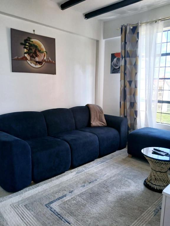 a living room with a blue couch and a table at Cozy Haven kitengela in Makandara