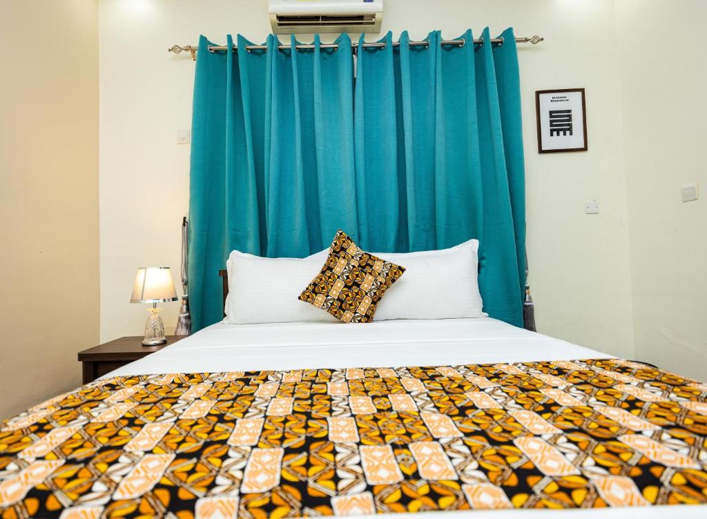 a bedroom with a bed with a blue curtain at Akwaaba Fie in Accra