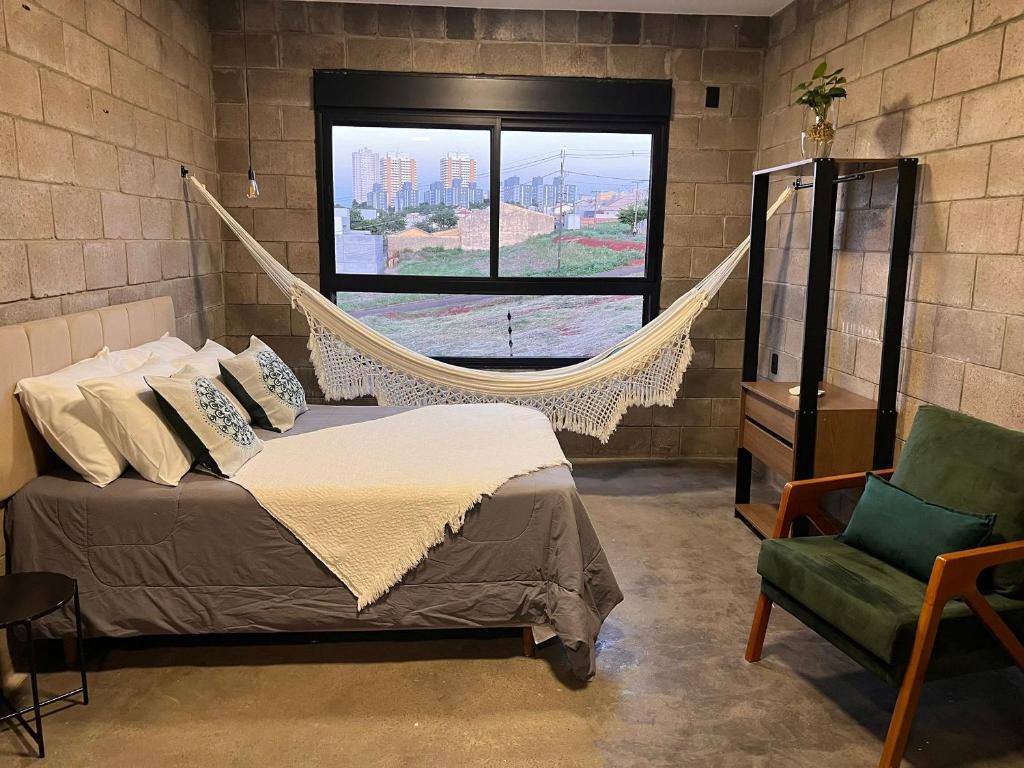 een slaapkamer met een hangmatbed en een stoel bij Kazuo520 - Studios Industriais Confort in Londrina
