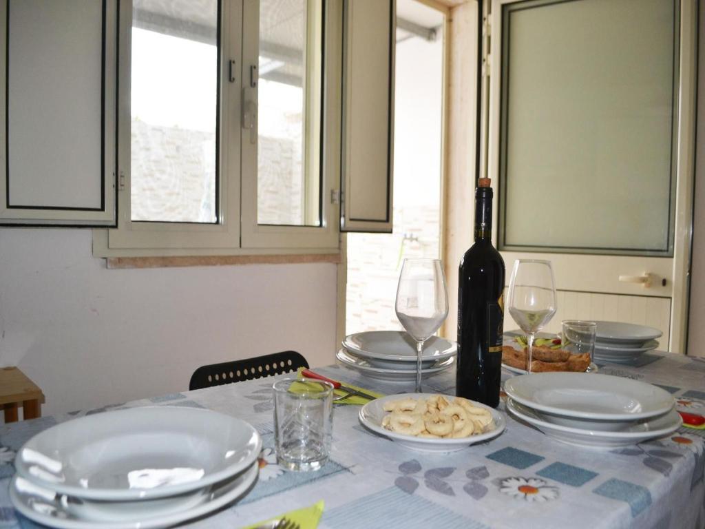 einen Tisch mit Tellern und Gläsern sowie eine Flasche Wein in der Unterkunft TSUKY Holiday Home in Torre dellOrso in Torre dell'Orso