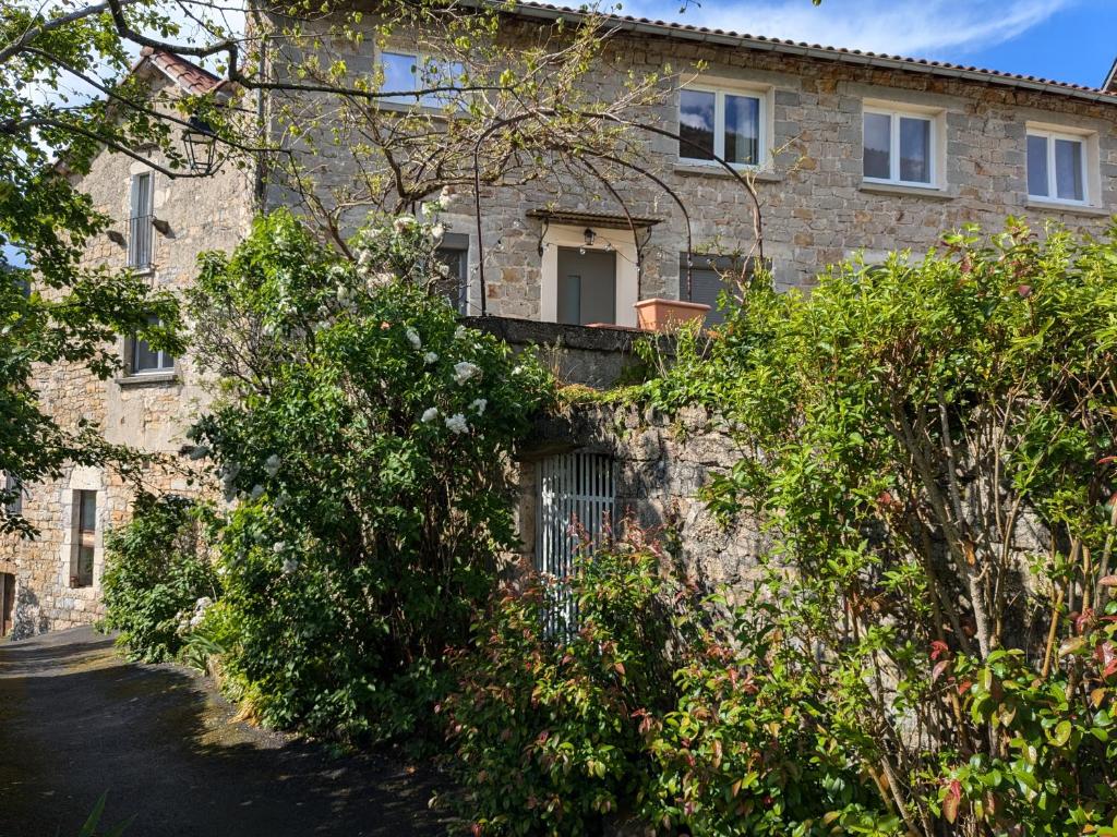 un bâtiment en briques avec des buissons devant lui dans l'établissement Au bord du Tarn, à Vabre
