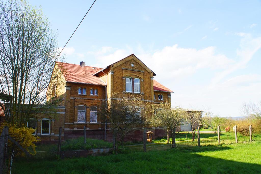 une maison en briques avec un toit rouge sur un champ vert dans l'établissement Alte Mühle Kelbra - ehemalig ALBIG, à Kelbra