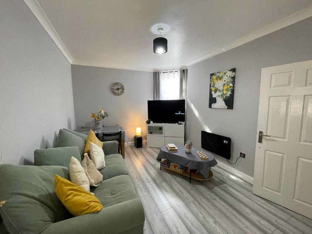 a living room with a green couch and a television at City Life Access Everywhere in London