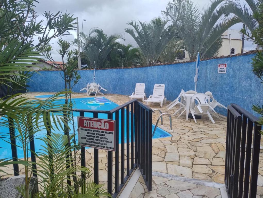 a fence with a sign in front of a swimming pool at Colônia de Férias Beleza e Arte in Caraguatatuba