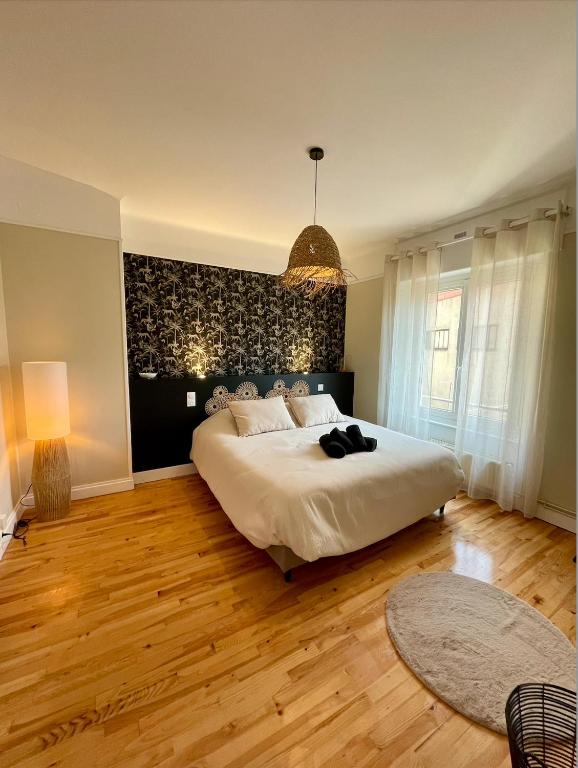 une chambre avec un grand lit blanc et du parquet dans l'établissement Le Nid Cosy, studio, à Saint-Dié-des-Vosges