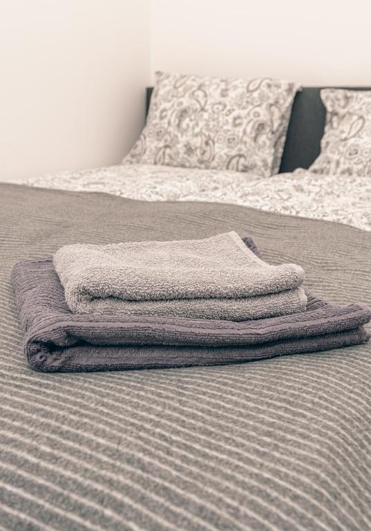 una pila di asciugamani appoggiata sopra un letto di L & S Apartmani a Sombor
