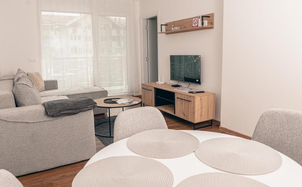 un soggiorno con tavolo e TV di L & S Apartmani a Sombor