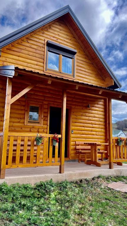 a log cabin with a porch and a bench at Alfa Omega Žabljak in Žabljak