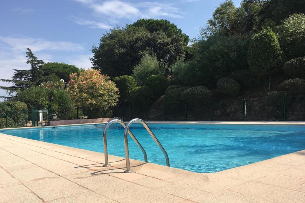 une piscine avec de l'eau bleue et des arbres en arrière-plan dans l'établissement Quiet flat with private garden, à Vallauris