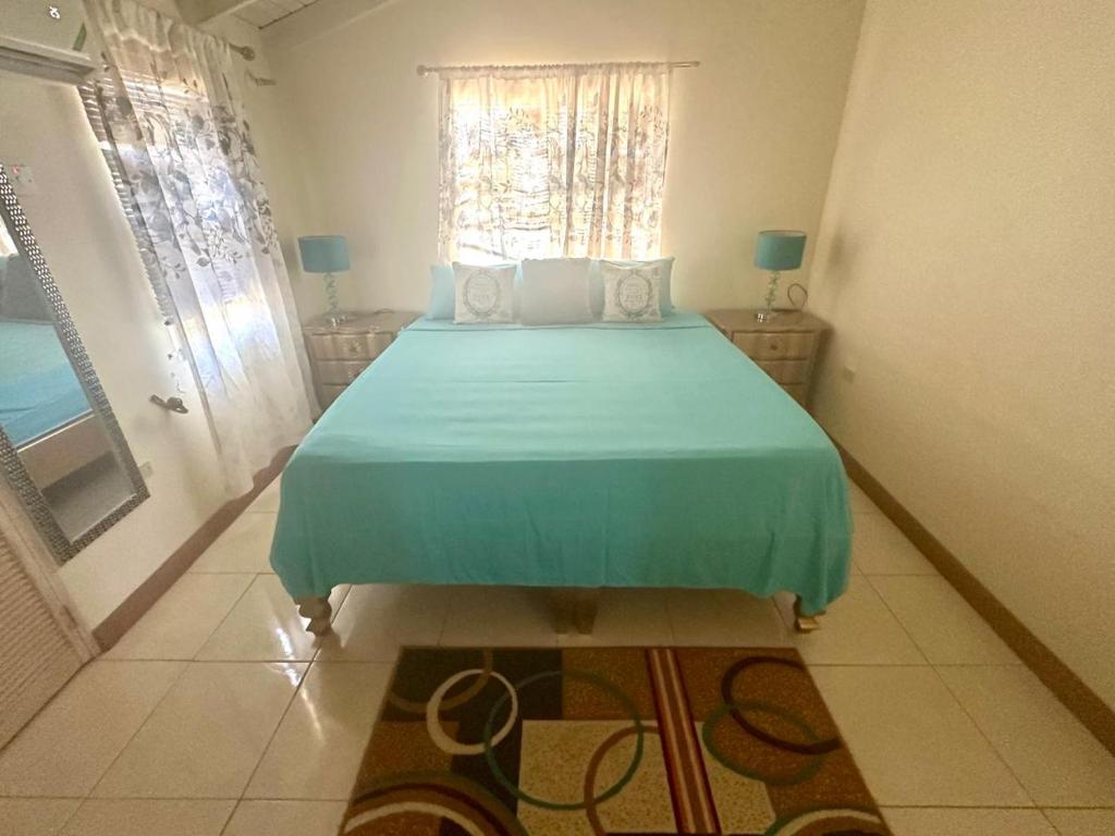 a bedroom with a bed with a blue bedspread and a window at Spring Top Cottage in Falmouth