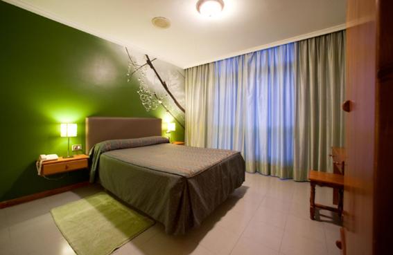 a bedroom with a bed and a green wall at Hostal Restaurante Terra Chá in Villalba