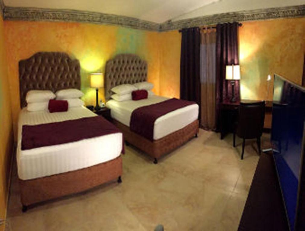 Habitación de hotel con 2 camas y TV en Antigua Inn Hotel, en Guatemala