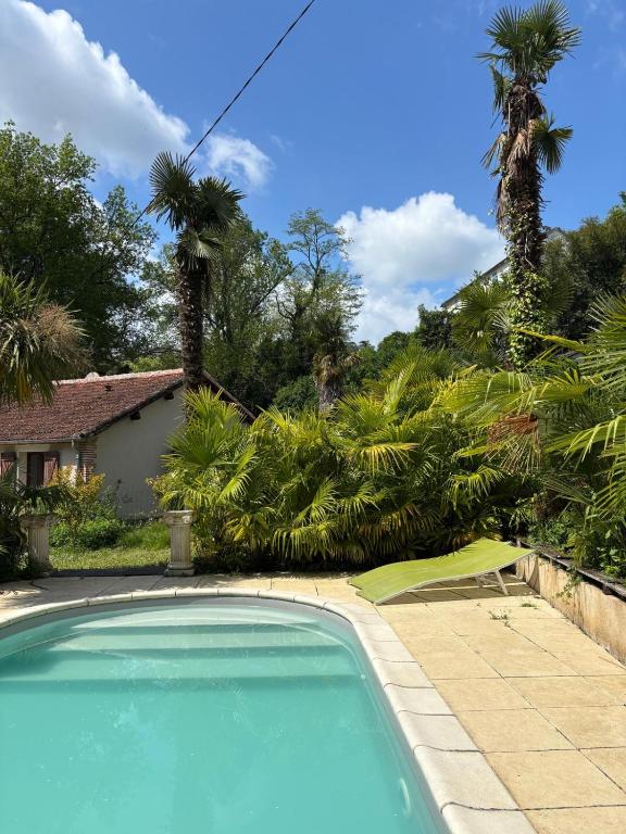 une piscine devant une maison avec des palmiers dans l'établissement Les palmiers de Valence, à Valence