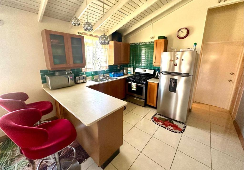 a kitchen with a stainless steel refrigerator and red chairs at Spring Top Cottage in Falmouth