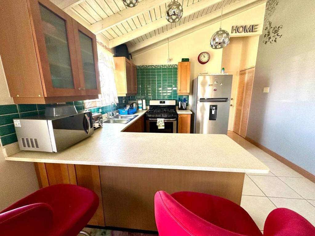 a kitchen with a counter and two red chairs at Spring Top Cottage in Falmouth