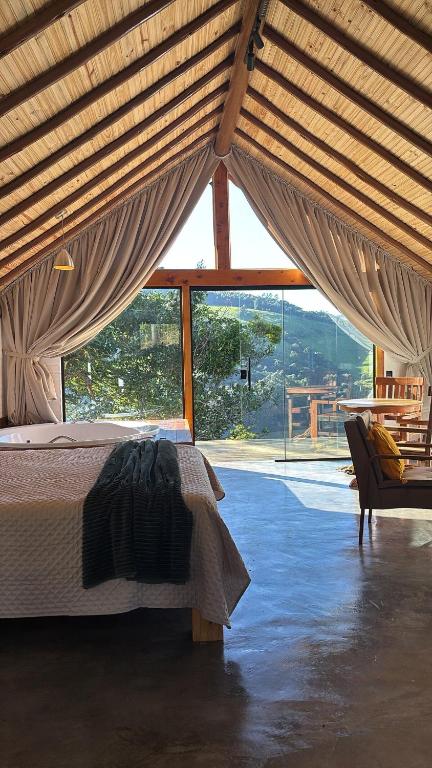a bedroom with a bed and a large window at Belo Nascer 2 in Joanópolis