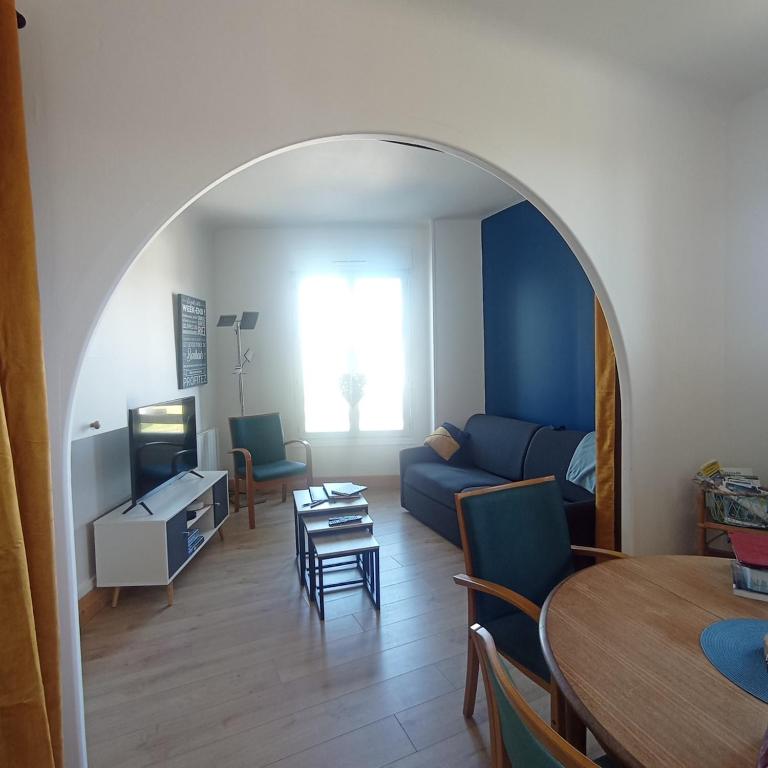 un salon avec un canapé bleu et une table dans l'établissement La Marinière, appartement avec garage, 2 étoiles à 100m de la mer, à Barneville-Carteret