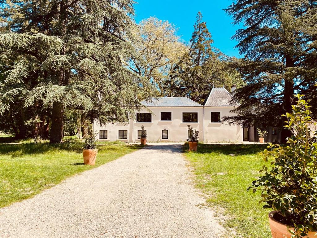 une allée menant à une maison blanche avec des arbres dans l'établissement Chateau et piscine privé près du Chateau de Chambord, à Lanthenay