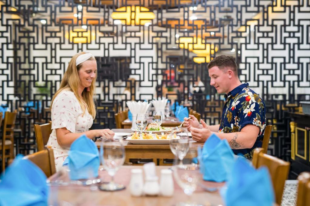 a man and woman sitting at a table eating food at Fivitel Hoi An Hotel in Hoi An