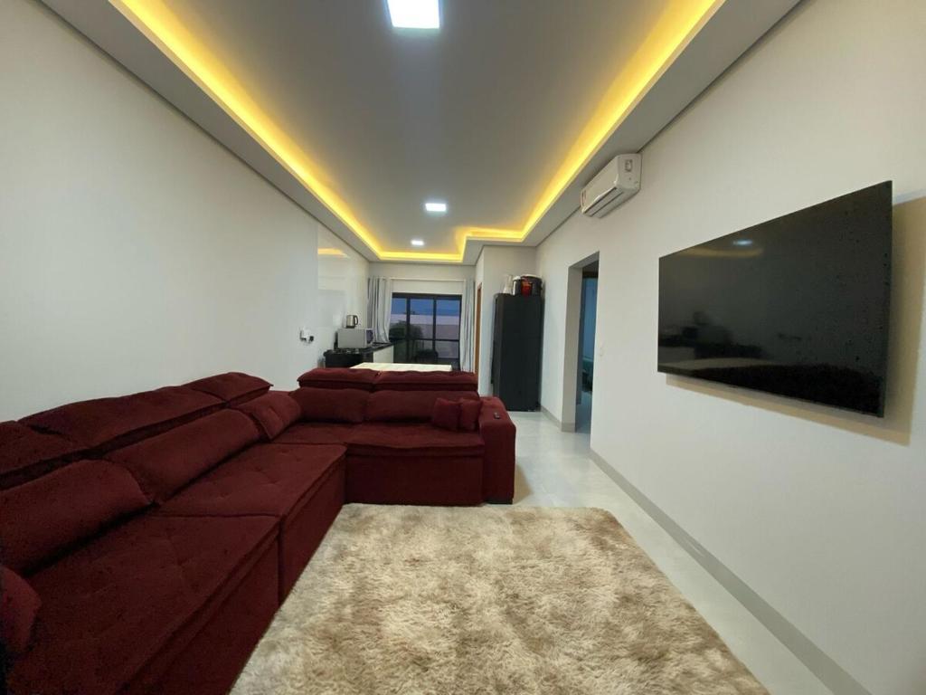 a living room with a red couch and a tv at Apartamento novo no centro de Sinop! in Sinop