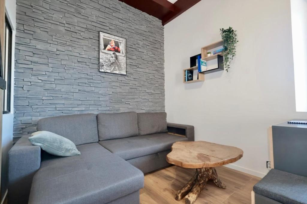un salon avec un canapé et un mur de briques dans l'établissement L'Atelier - Apt 2 Prs vue Mer - Clim - parking, à Vallauris