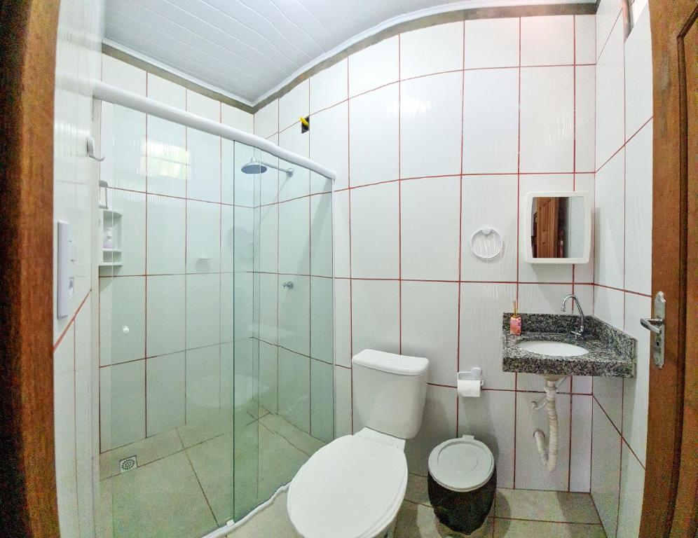 une salle de bain avec toilettes et douche en verre dans l'établissement Hospedaria Oliveira - Santo Amaro do Maranhão, à Queimada