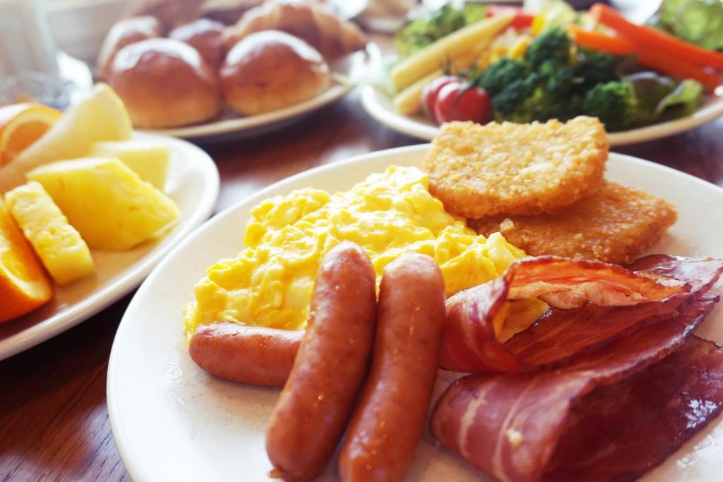 Richmond Hotel Premier Tokyo Schole في طوكيو: طبق من طعام الإفطار مع البيض والنقانق وأطعمة أخرى