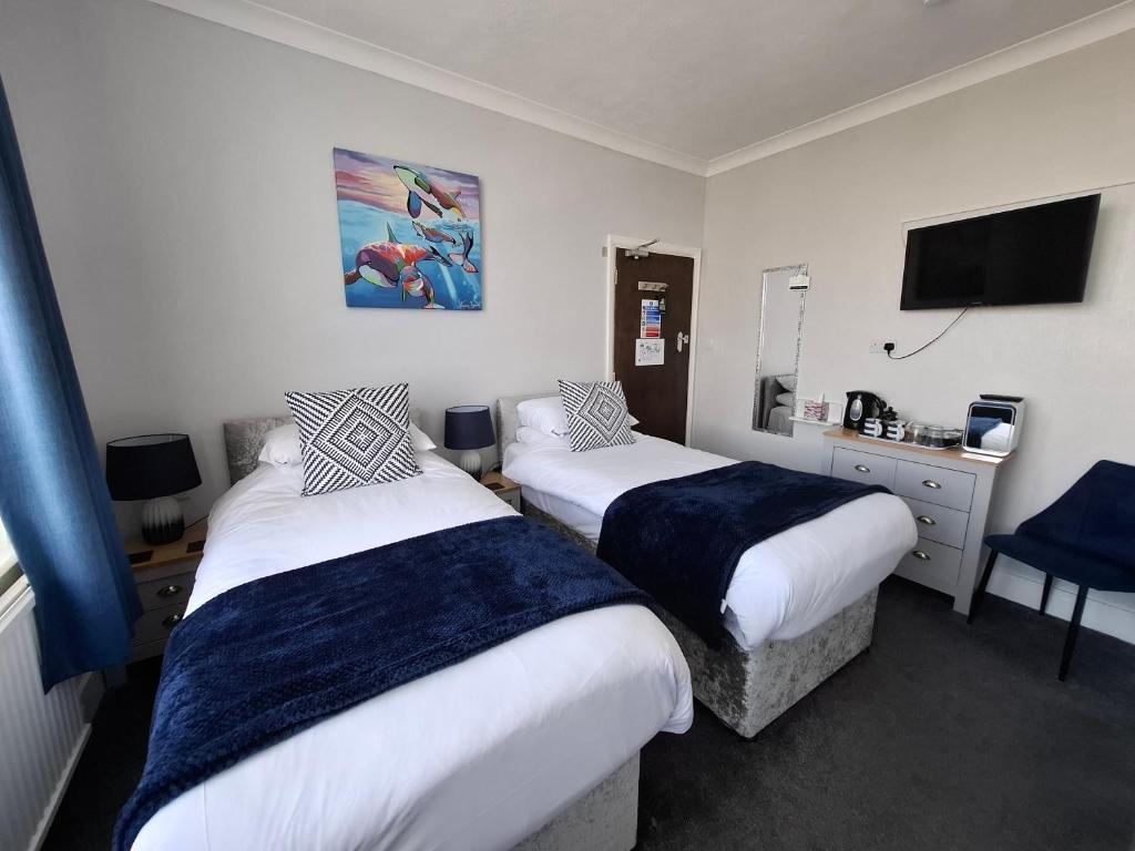 a hotel room with two beds and a television at Westbrook Lodge Guest House in Margate