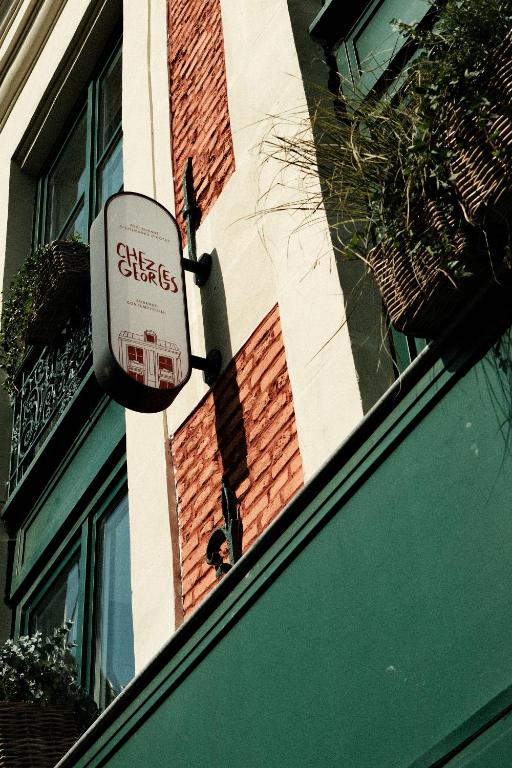 un panneau se trouve sur le côté d'un bâtiment dans l'établissement Chez Georges - Auberge Contemporaine, à Lille