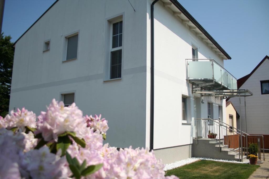 ein weißes Gebäude mit einem Balkon und rosa Blumen in der Unterkunft Gästehaus Karassowitsch in Rust