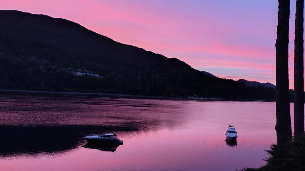 two boats floating on a lake at sunset at Dos Bahias Lake Resort in Villa La Angostura