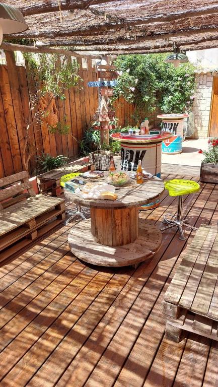 une terrasse en bois avec une table et des chaises. dans l'établissement Charmant T2 à 5min des plages, à Port-la-Nouvelle