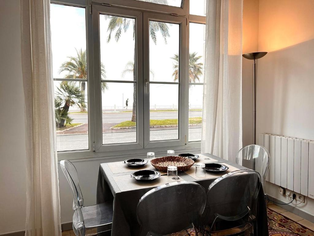 une table avec des chaises devant une grande fenêtre dans l'établissement Studio Promenade, à Nice