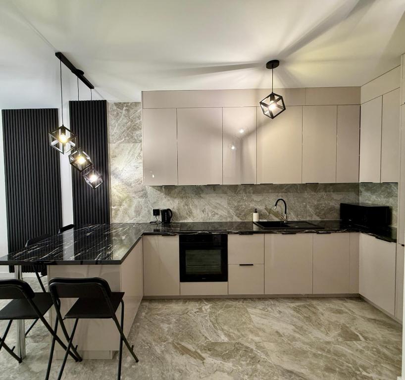 una cucina con mobili bianchi e un piano di lavoro nero di Drahan Apartment 14 a Radom