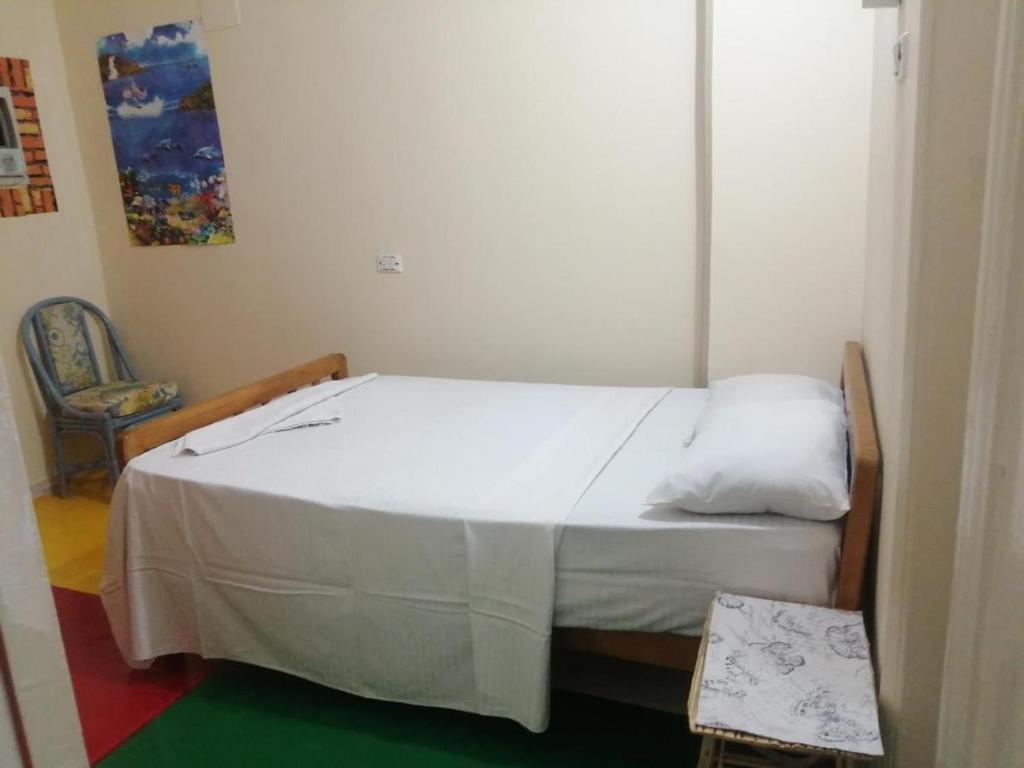 a bedroom with a white bed with a chair at La Gazelle Guest House in Butare