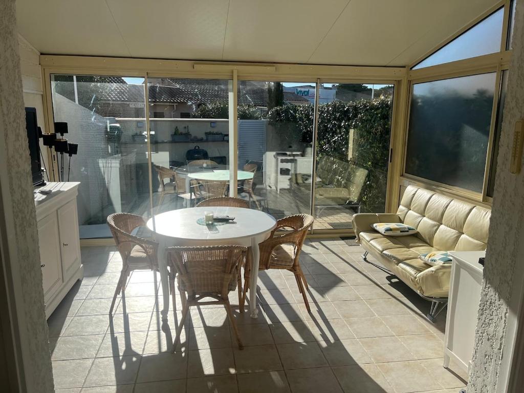 une cuisine avec une table, des chaises et un canapé dans l'établissement Maison rivage bleu 4 pers 2 sdb clim wifi, à Gruissan