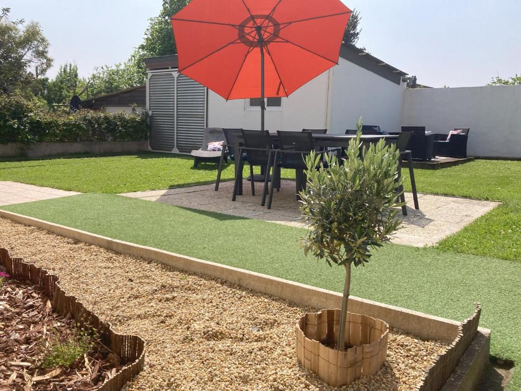 d'une terrasse avec une table et un parasol rouge. dans l'établissement Maison cosy Futuroscope, à Jaunay-Clan
