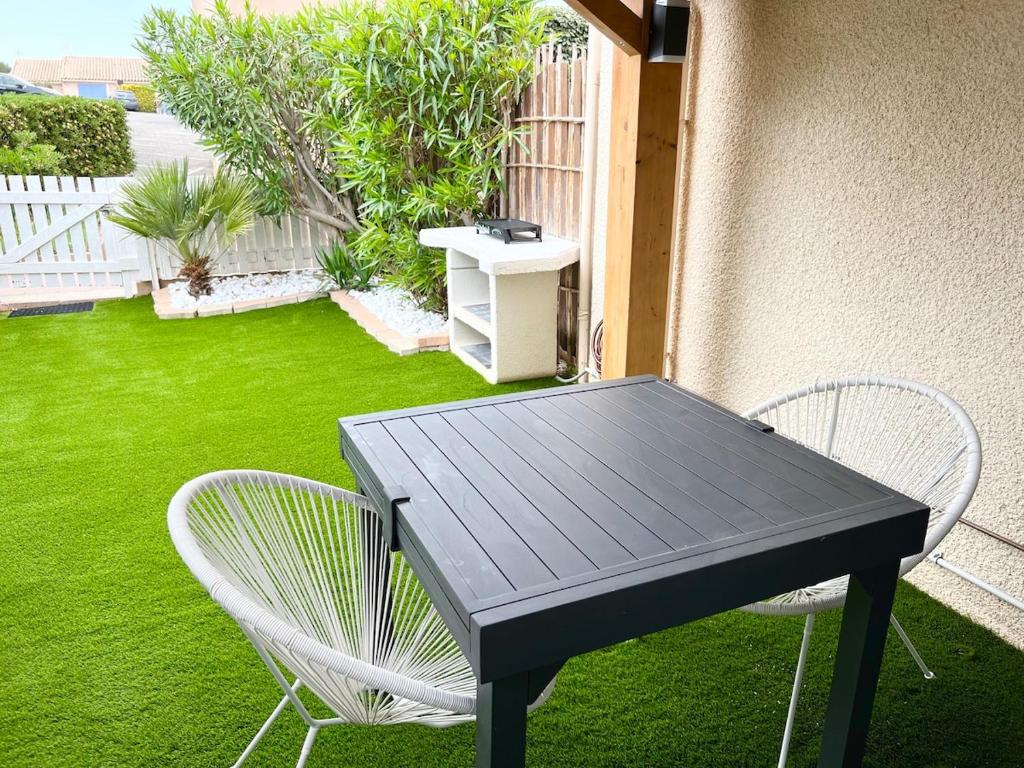 une table noire et deux chaises sur une terrasse dans l'établissement Pavillon avec jardin et piscine saisonnière, à Gruissan