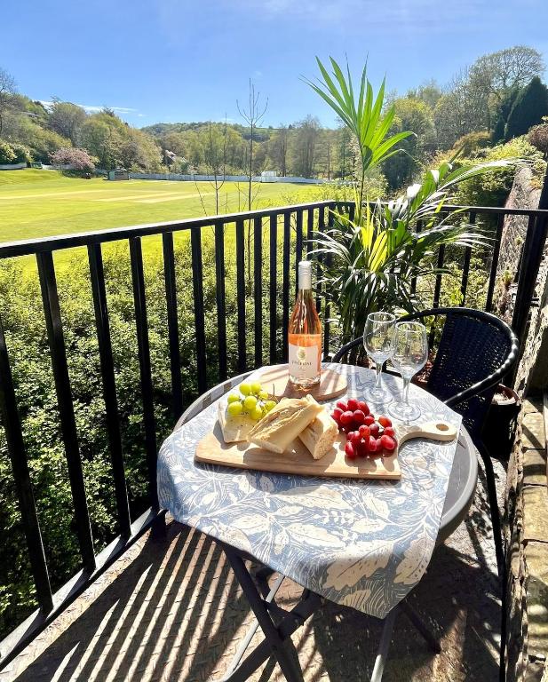 a table with a plate of food and a bottle of wine at Wicket Green Cottage Hayfield in Hayfield