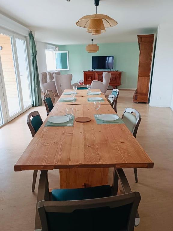 une grande table en bois dans une pièce avec des chaises dans l'établissement Quiet shared getaway, à Giberville