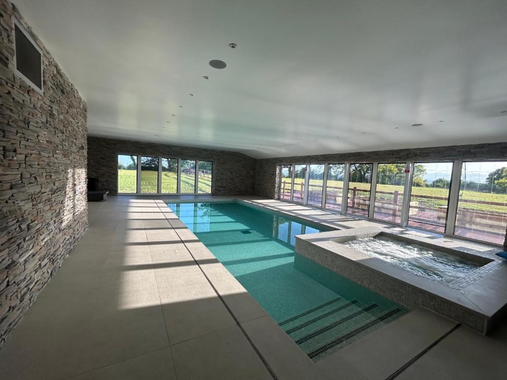 a large swimming pool in a building with windows at Four Bedroom House With Private Pool - Stunning countryside location with parking close to Chester City Centre in Chester