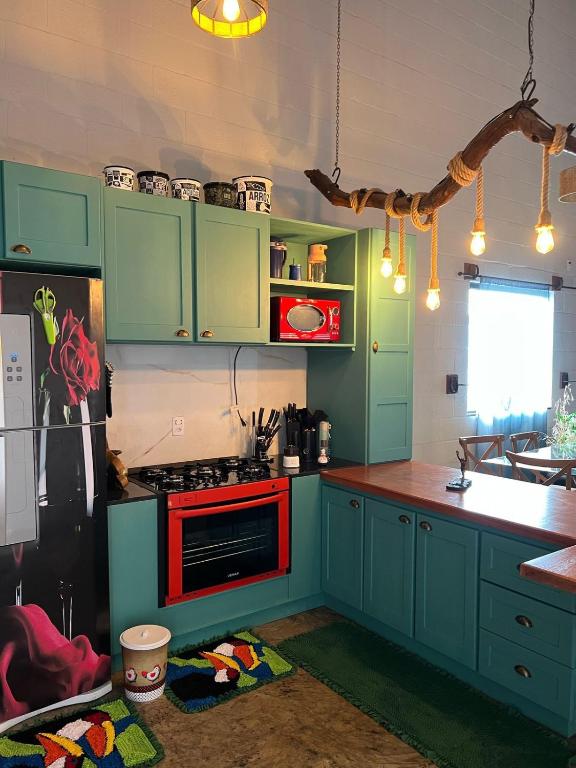 a kitchen with green cabinets and a red stove top oven at Recanto do sossego in Sinop