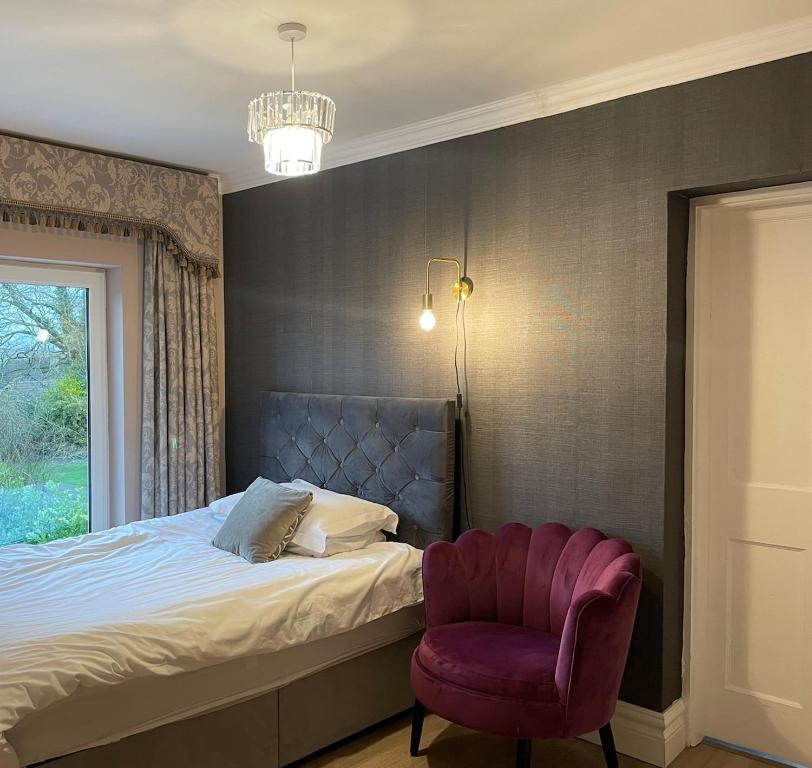 een slaapkamer met een bed en een paarse stoel bij The Masters House, Castledermot in Feevaghmore