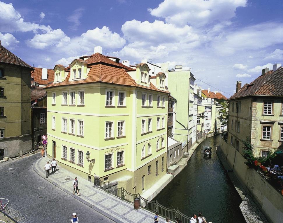 um edifício amarelo ao lado de um canal numa cidade em Hotel Certovka em Praga